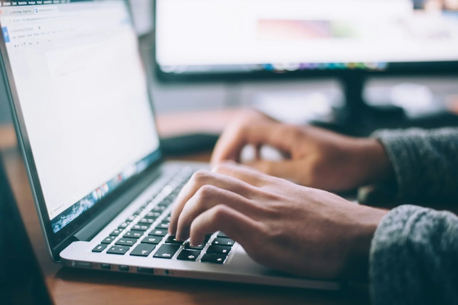 Persona trabajando con varios monitores, tecnología en el despacho