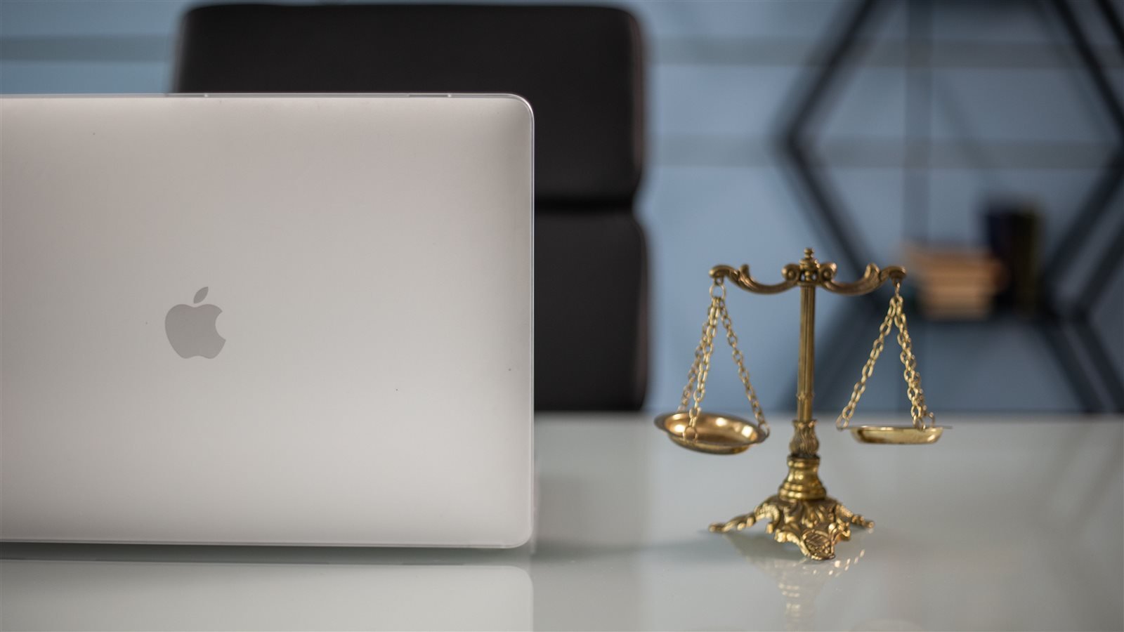 Una balanza de la justicia dorada junto a un portátil sobre una mesa de despacho, simbolizando la digitalización de la Administración de Justicia
