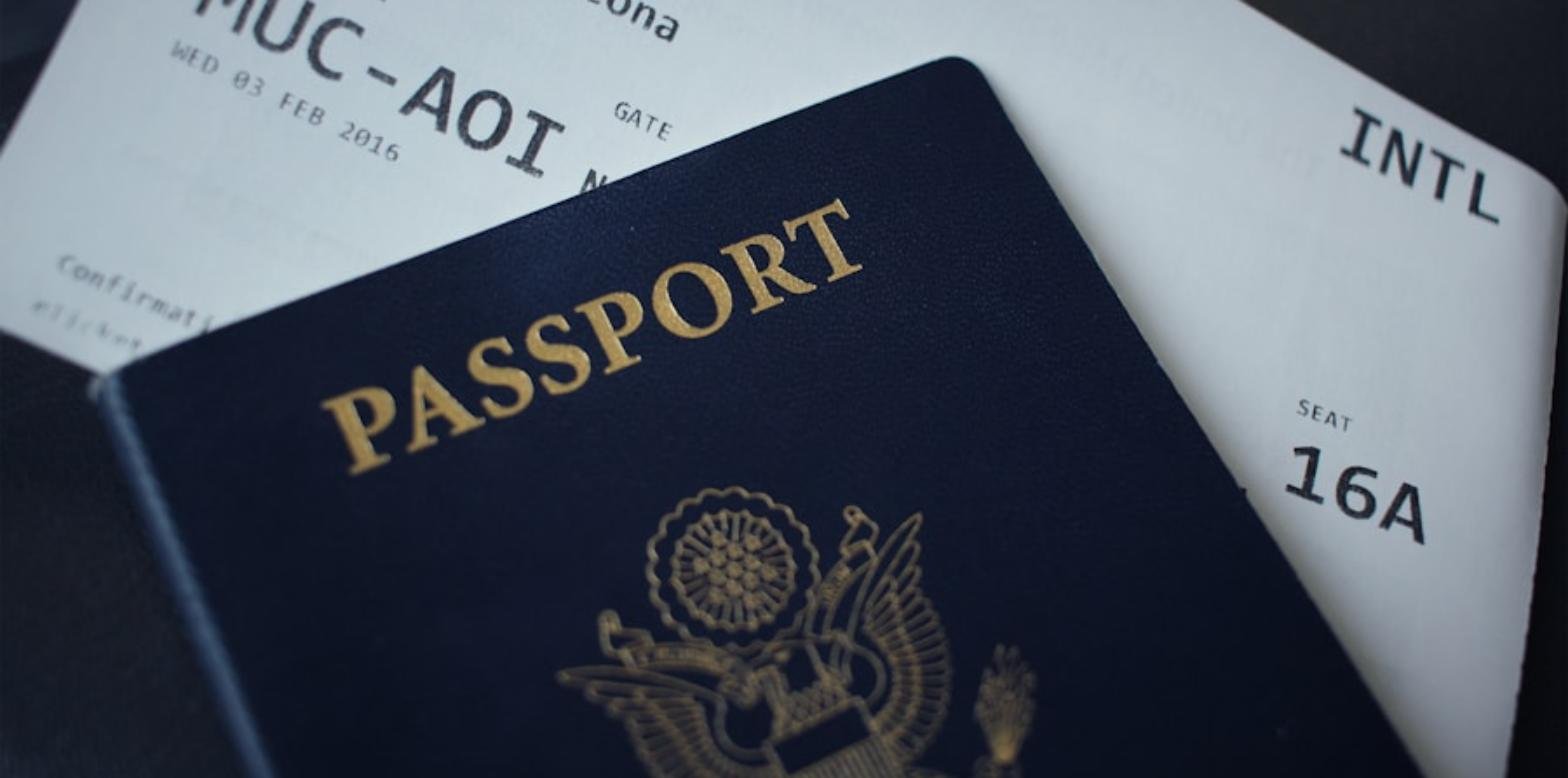 Un pasaporte junto a una tarjeta de embarque, sobre un fondo oscuro