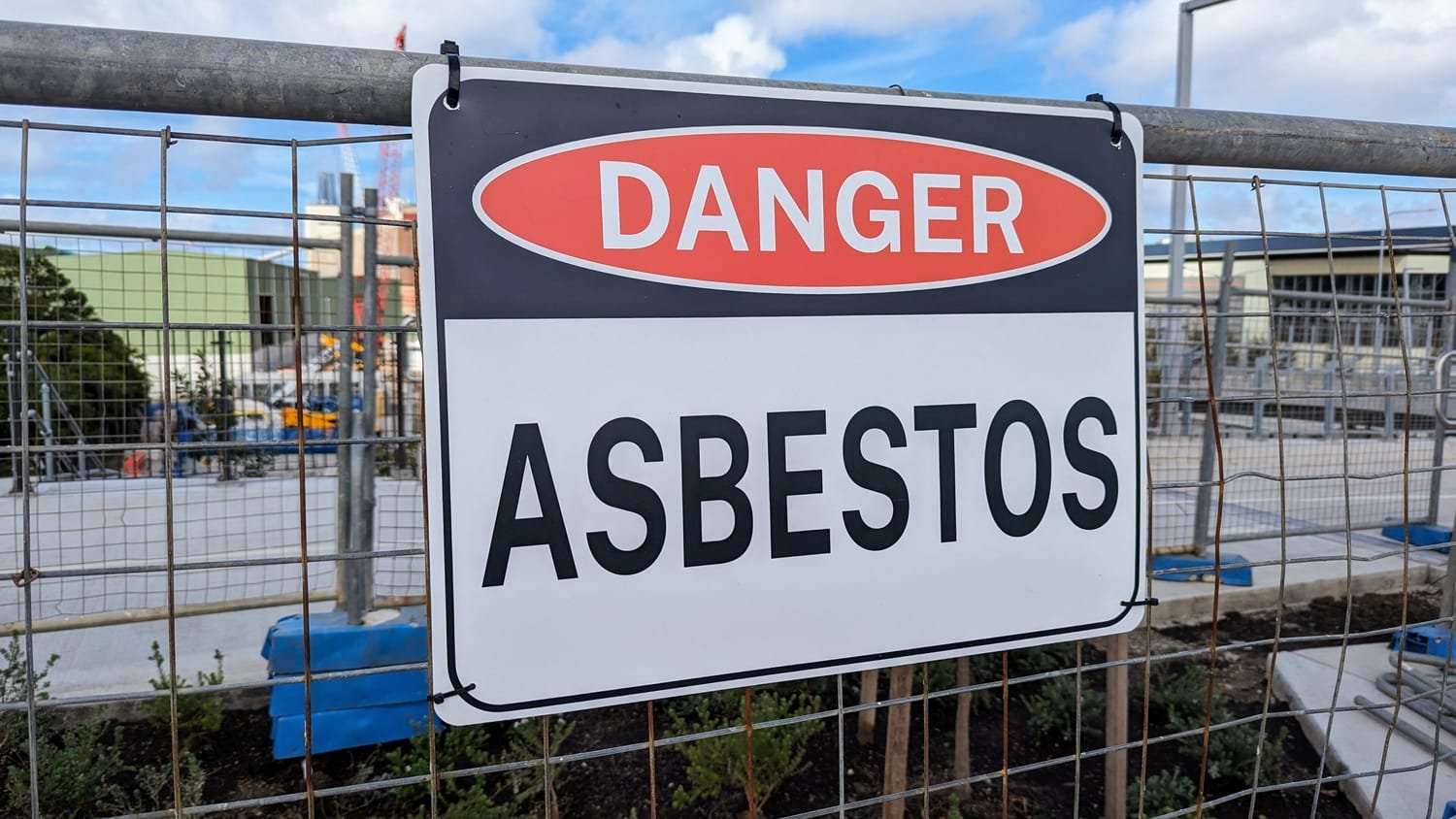 Cartel «Danger – Asbestos» colgado en la valla de una obra